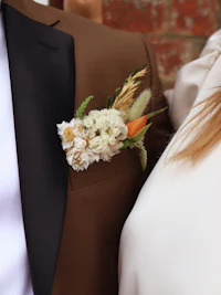 a man in a brown suit with a flower boutonniere