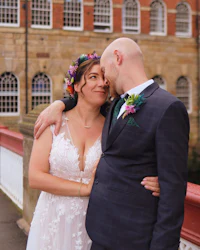 a bride and groom embracing on a bridge