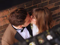 a couple kissing in front of a brick wall