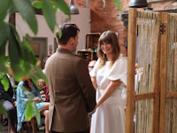 a bride and groom exchange vows in front of a wooden wall