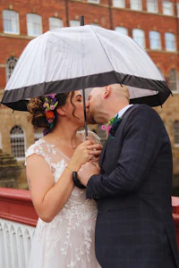 a bride and groom kiss under an umbrella
