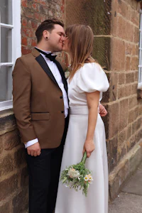 a bride and groom kissing in front of a brick wall