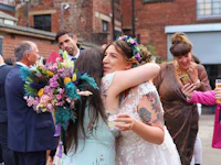 two brides hugging in front of a crowd of people