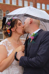 a bride and groom kissing under an umbrella