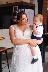 a woman in a wedding dress holding a baby