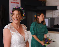 a bride in a flower crown smiles in front of a group of people