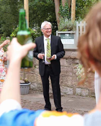a man in a suit is holding a bottle of beer