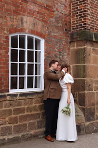 a bride and groom kissing in front of a brick building