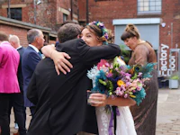 a bride and groom hugging in front of a crowd of people