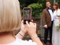 a woman taking a picture of a bride and groom