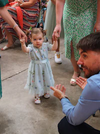 a little girl is holding hands with a man at a wedding