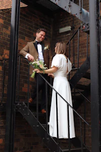 a bride and groom standing on the stairs of a brick building